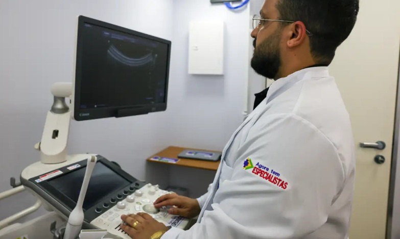 Médico realiza ultrassonografia com equipamento moderno.